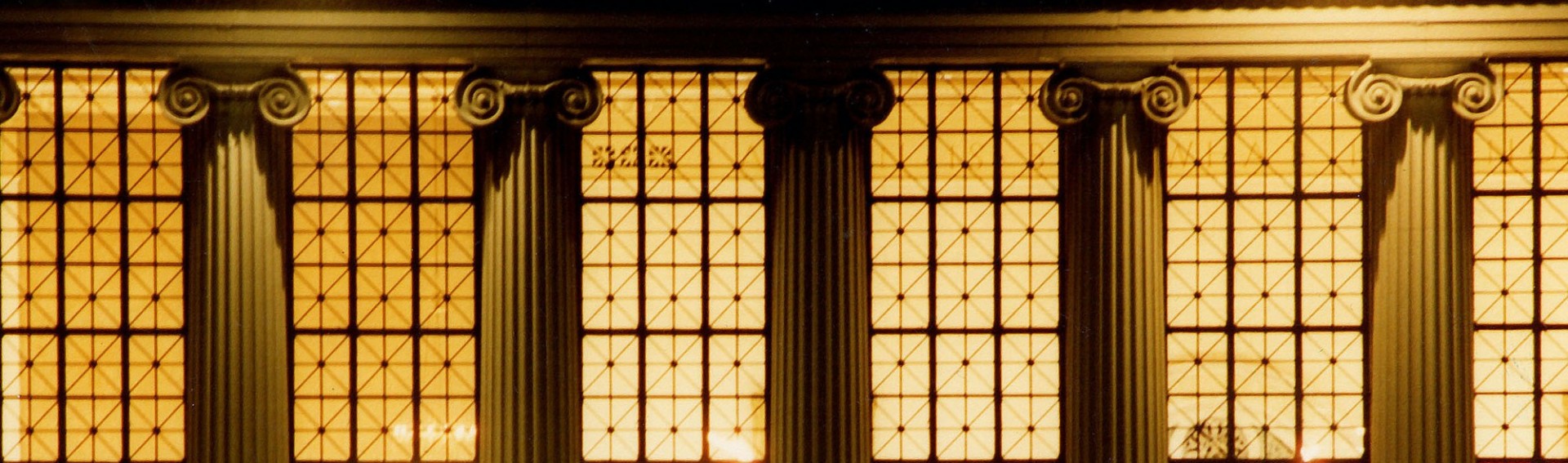 Image of Columbia University's Butler Library, displaying the exterior windows and pillars at night